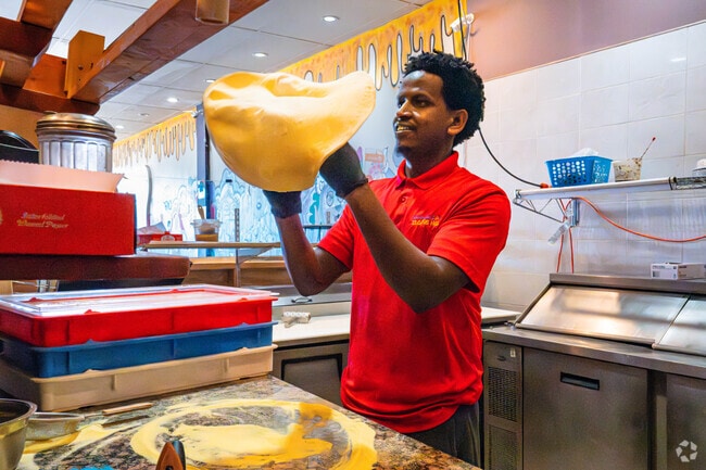 Experience the mesmerizing art of pizza spinning at Stone Hot Pizza in Hayfield Center.