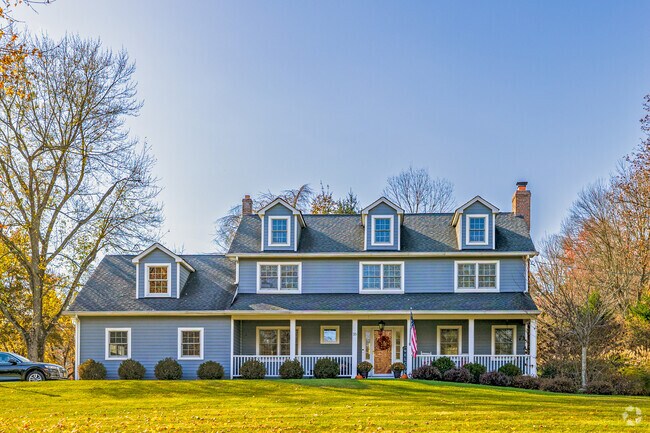 Blue colonial-style home with wrap-around porch in Mendham’s historic residential area.