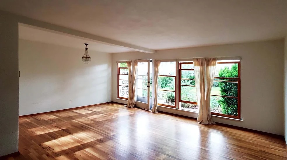 Living / dining room with floor-to-ceiling wood windows that open to private courtyard
