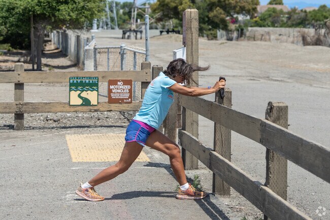 A lady stretches out after a run along the Bay Trail near Longwood.