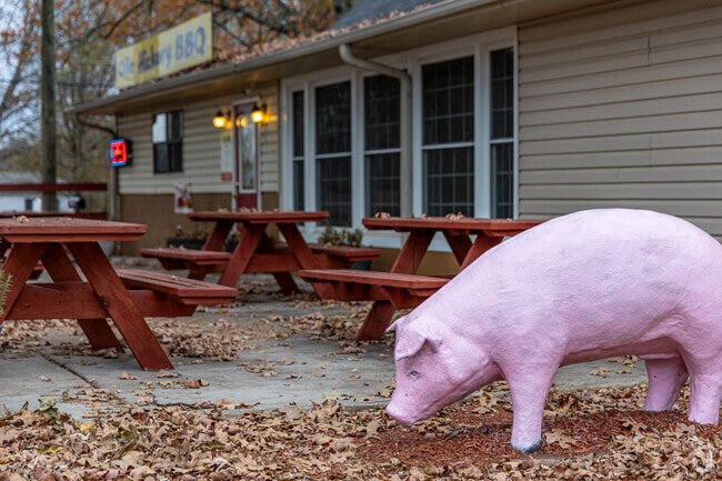 Ole Hickory BBQ has a pig statue and outdoor picnic tables to enjoy your meal on.
