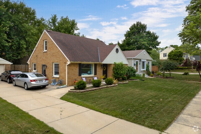 This classic brick home looks charming under a blue sky on a summer day.