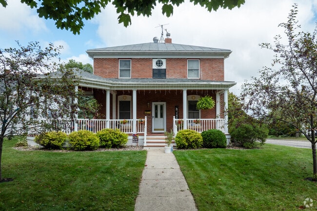 This brick Victorian home in Caledonia features a green lawn and front porch.