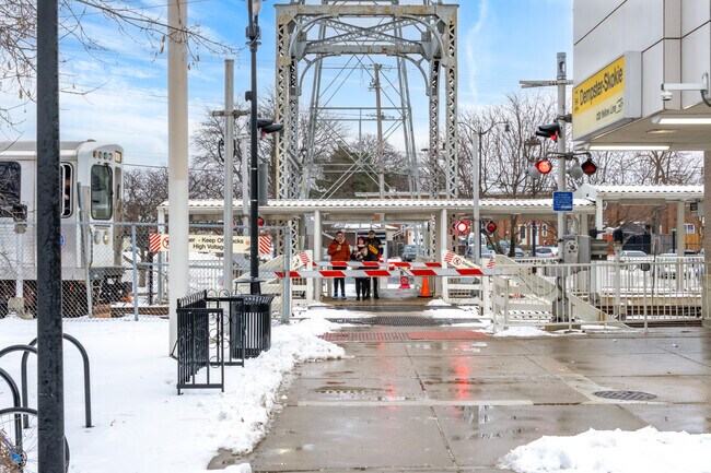 Patrons wait at the rail crossing at the Dempster yellow line CTA train station.
