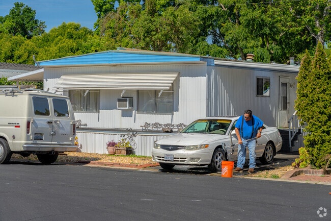 A man washes his car in front of mobile home in Michigan-Glide-Sutter.