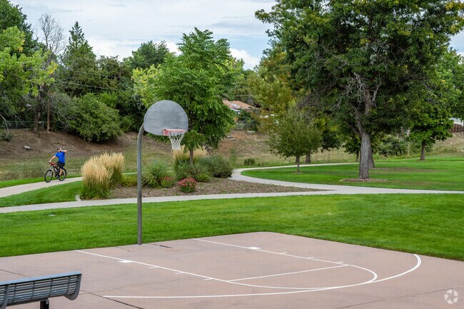 A cyclist rides along the bike path near the basketball court at Little Dry Creek Park in Arvada