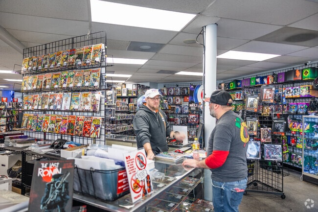 Jay serving his customer at Jay's Comics, surrounded by superheroes and action figures.