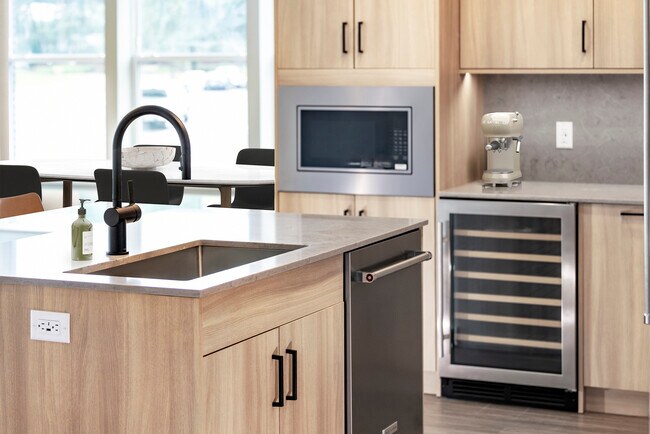 Signature Collection kitchen with stainless steel appliances (wine fridge included), quartz countertops, quartz tile backsplash, oak cabinetry, and hard-surface flooring