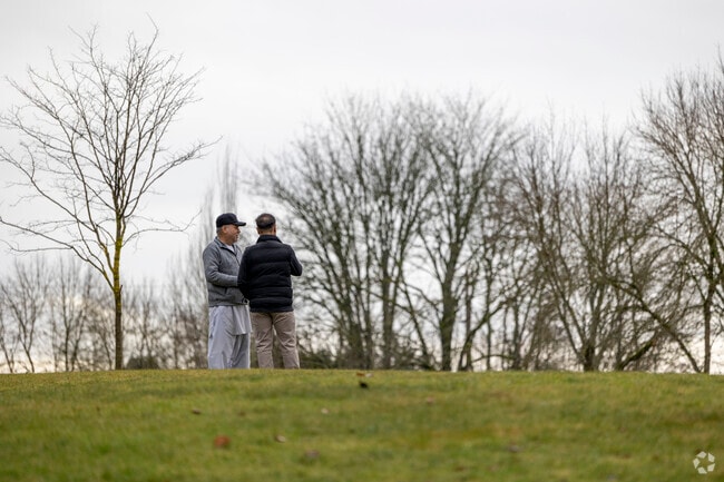 Two pedestrians enjoy Lake Meridian Park on a cloudy, rainy winter day.