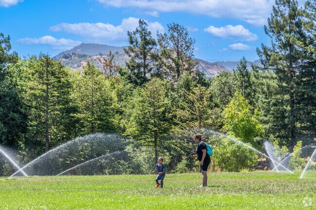 A mother and daughter exhilarate in cooling off in the sprinklers at Newhall Community Park.
