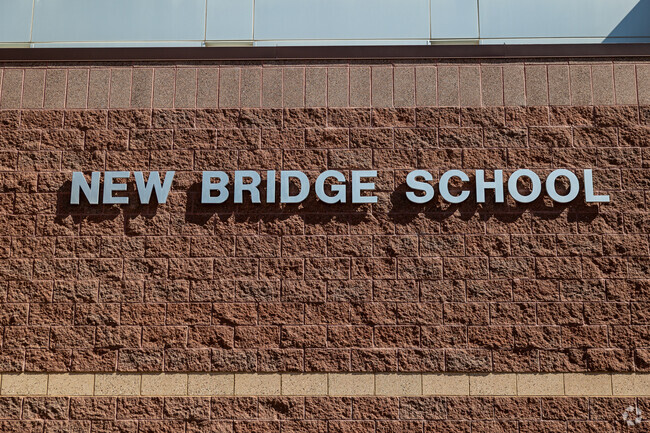 New Bridge School is spelled out in metal letters on a brown wall.