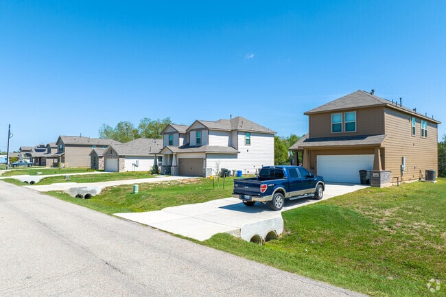 A row of homes with spacious yards sit alongside a peaceful neighborhood road.
