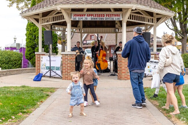 Kids dance joyfully in front of the gazebo as a live band plays at the farmers market.