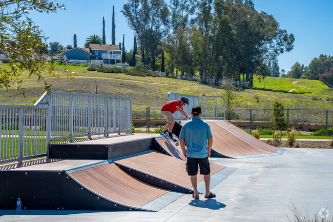 Grandkids play freely while grandpa smiles nearby at Long Canyon Creek Park in Meadowview, Temecula.