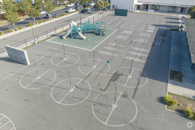 The play area at Ruby Bridges Elementary School is mostly concrete but there is some grass too.