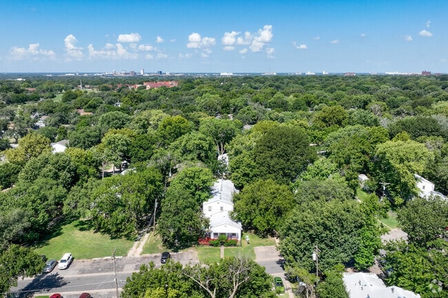 Hilltop homes are surrounded by tall trees.
