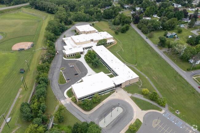 The campus of Herkimer High School is surrounded by trees and is still in the urban area.