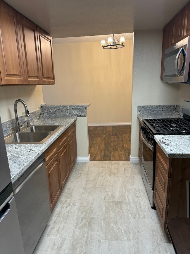 Kichen with SS appliances, marble counters and porcelain tiles.