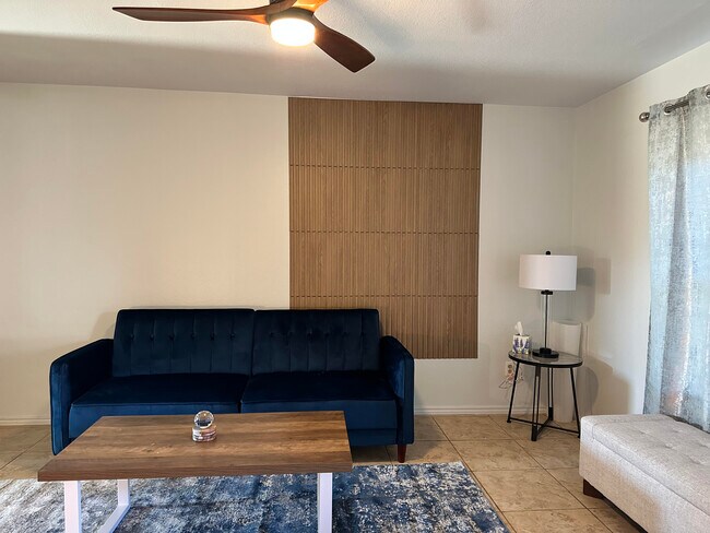 Living room fully furnished with brand new sofa, chair, large screen tv, and fresh coat of paint