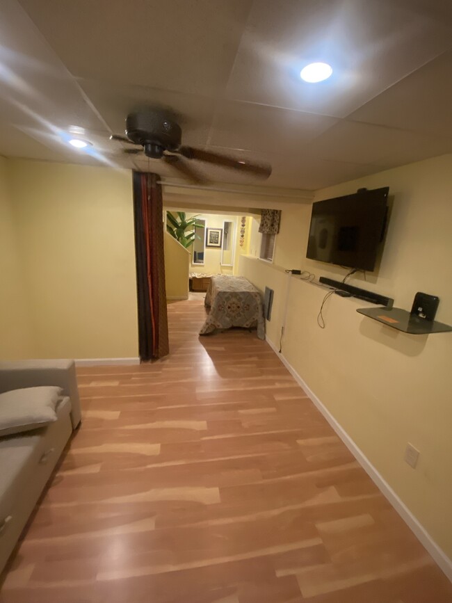 view from living room towarsd to walkway outside/ sofa, small dinnette and tv vied