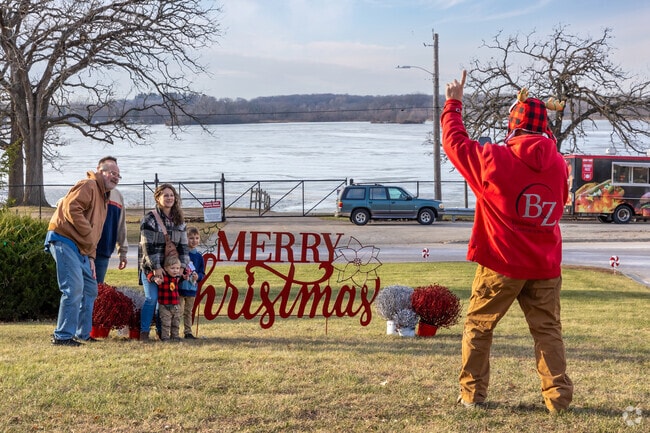 A family poses by a 'Merry Christmas' sign, capturing holiday memories with friends.