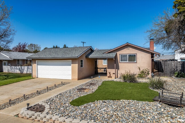 This ranch-style home has artificial grass and stucco siding in White Rock.