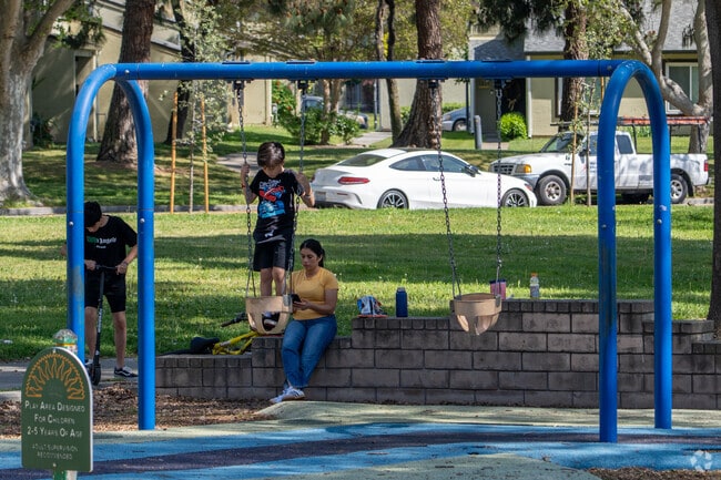 Families relax and play at Vinci Park in Vinci South, where swings and green space welcome all ages.
