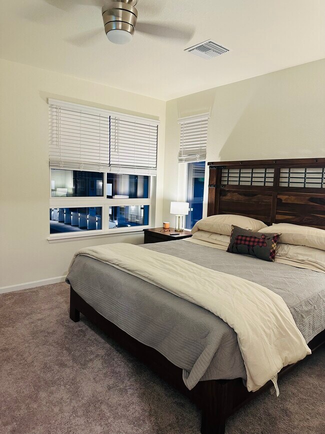 Large master bedroom with corner windows, a king bed, restroom and walk-in closet