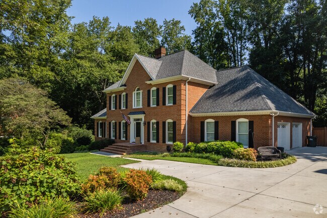 A brick colonial revival home surrounded by trees.