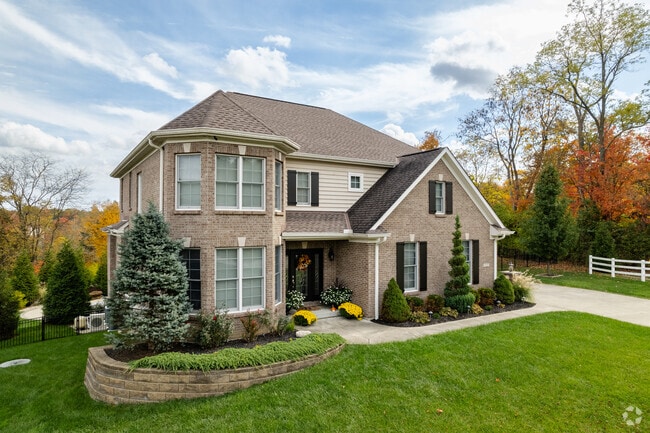 Two-story brick homes reflect the classic charm of Highpoint’s established neighborhood, featuring a landscaped front yard with colorful flowers and neatly trimmed bushes.