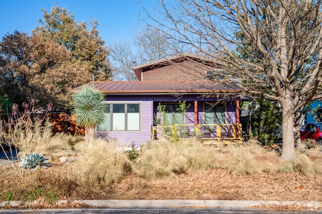 Crestview's charming purple bungalow stands proudly amidst the embrace of nature.