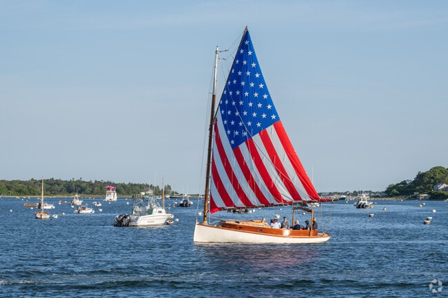 A patriotic sail catches the wind and propels the boat toward the exit of Edgartown Harbor