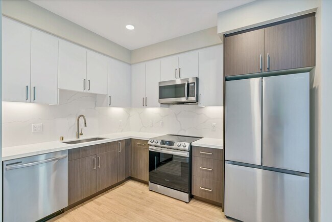 This full kitchen has a large sink, French-door fridge, dishwasher, microwave, and a stovetop oven.