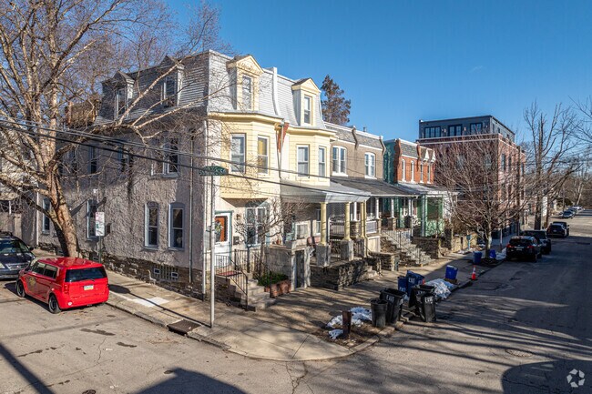 Rowhomes with mansard roofs sit next to red brick houses on this Chestnut Hill street.