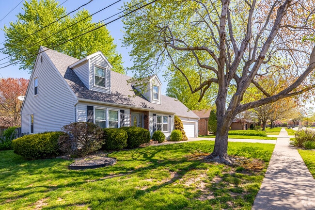 A large tree in Bradford Park shades a Cape Cod-style home with a garage.