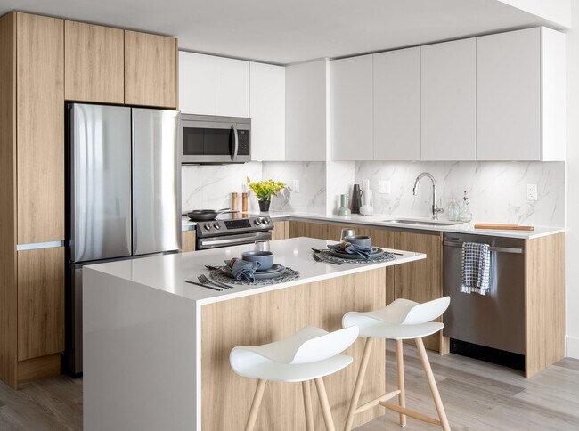 Kitchens feature modern energy star appliances, under-cabinet lighting, and a stone-wrapped island