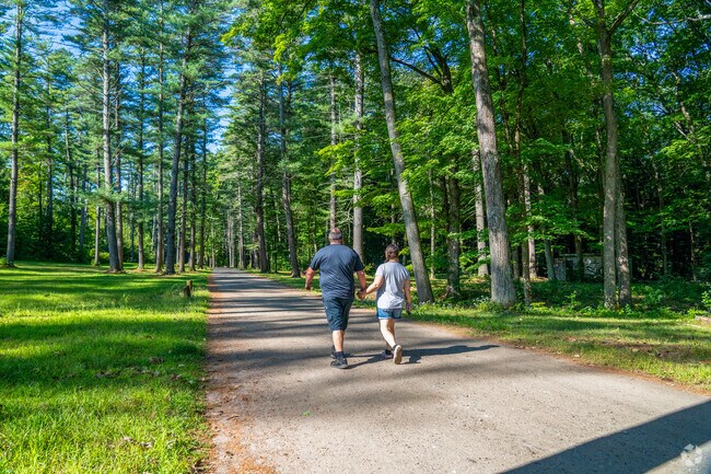 A couple strolls through dozens of tall trees at Moody Park in Maple Avenue District.