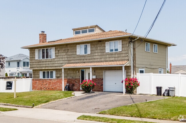 Rows of raised ranch-style houses line Lindenhurst streets, framed by neat green lawns.