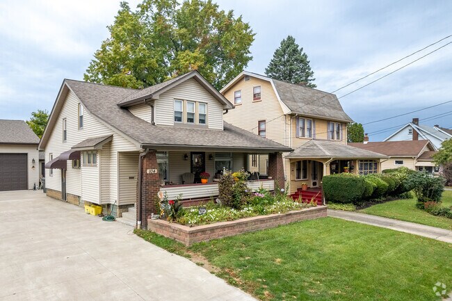 A folk-inspired cottage in Belle Vista features a covered porch and a flower bed.