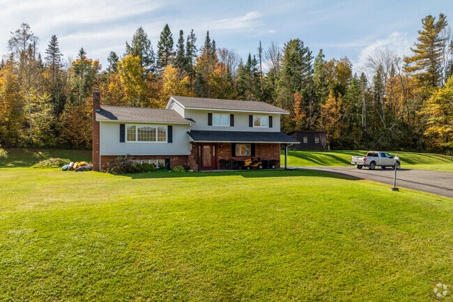 A bi-level style home in East Barre sits on a large plot of land with tall trees in the rear.