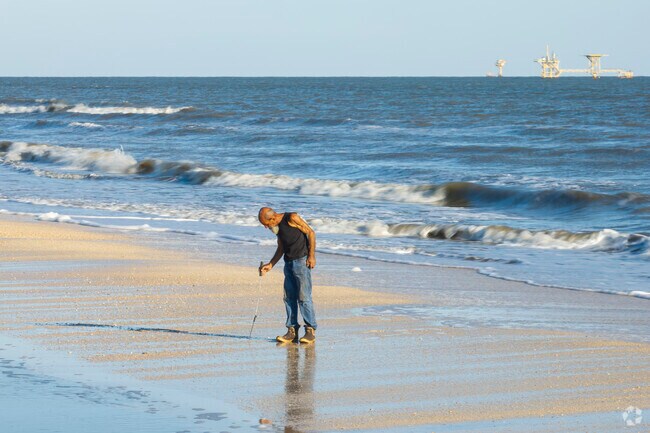 A local man walks the beach in Cameron in search of clams in the sand.