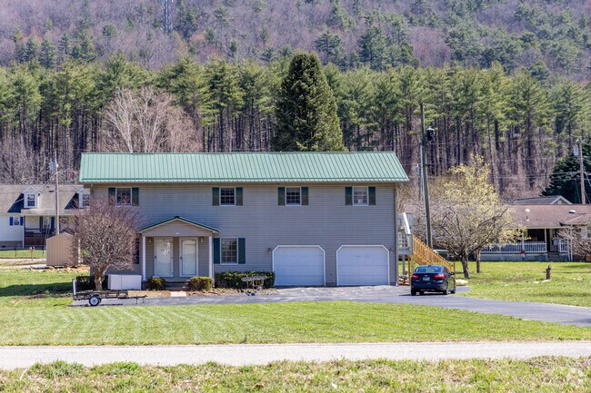 A large, multifamily home in the neighborhood of Hampton, TN sits on a large grass lot.