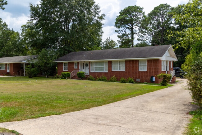 A peaceful suburban scene showcases a brick home with a large yard.