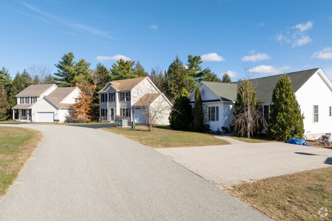 A quiet suburban street in Rindge, New Hampshire, lined with well-kept homes under a crisp blue autumn sky.