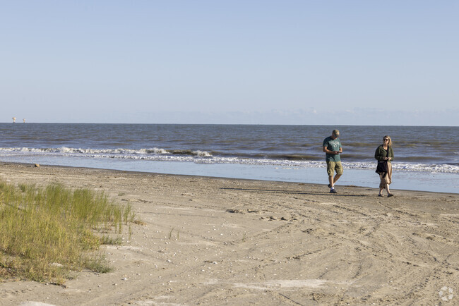 A couple visiting from Switzerland walk along Broussard Beach in Cameron.