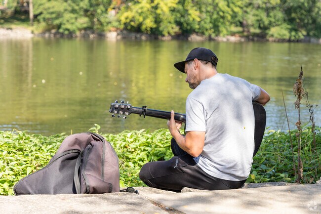 A resident practices his guitar along the Fox River in Downtown Oswego.