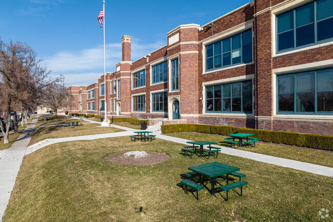 Manicured lawn have greens picnic tables in front of Rowland Hall.