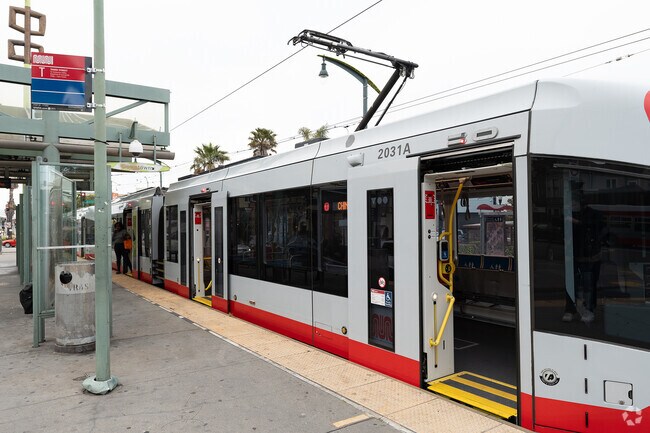 Muni light rail train making a stop on bustling 3rd Street in Hunter's Point.