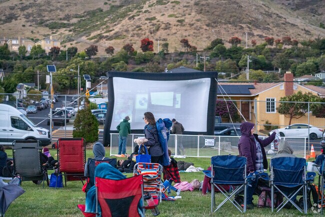 Community members bundle up as the screen lights up for Movie Night in the Park in SSF.