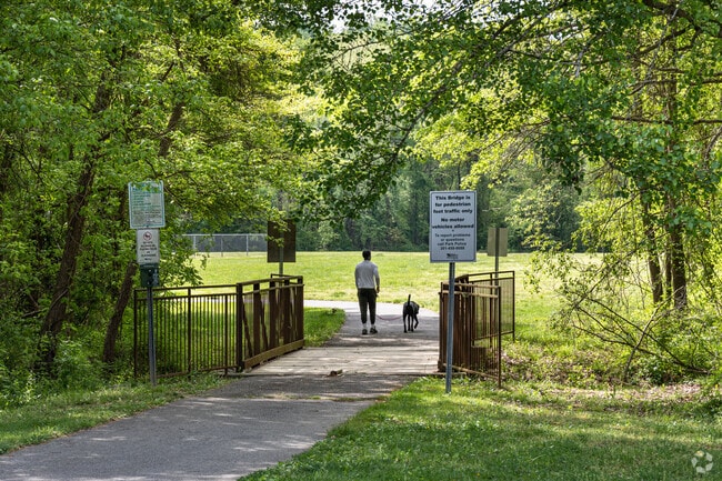 Locals take their dog for a walk on shaded trails at Hillantrae Community Park in Windbrook.